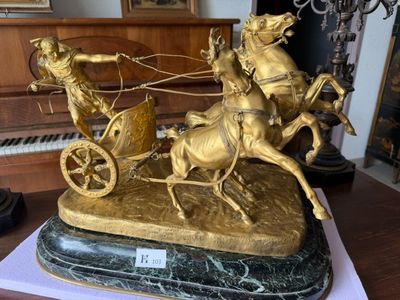 a gold statue of a man riding a horse drawn carriage