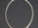a close up of a silver necklace on a black surface