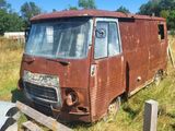 une vieille camionnette rouillée, garée dans un champ bordé d'une clôture en bois