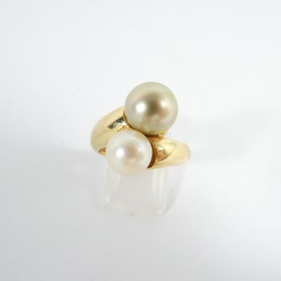 une image représentant une bague en or et perles posée sur une surface blanche