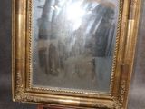 une photo d'un miroir à cadre doré posé sur un socle en bois