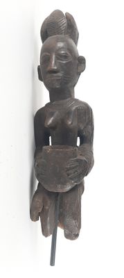 a wooden sculpture of a woman holding a bowl