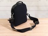 a black cross body bag sitting on top of a wooden table