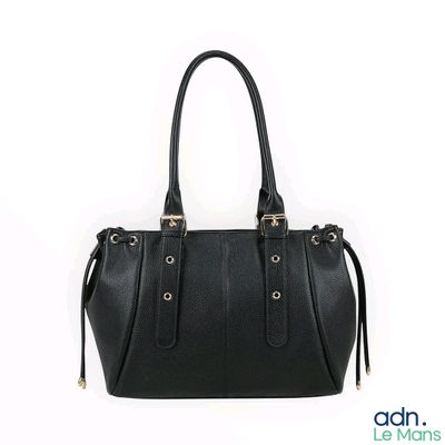 Le sac à main en cuir noir est posé sur une surface blanche.