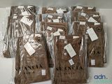 six paires de pantalons marron sont emballées dans des sacs en plastique sur une table