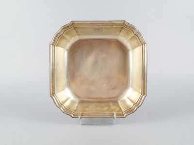 une assiette en or posée sur un socle, sur une surface blanche