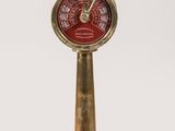 une horloge ancienne en laiton avec un cadran rouge sur fond blanc