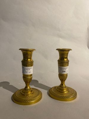 two gold candles that are sitting on a white table