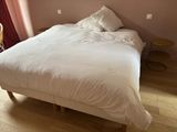 un lit avec des draps et des oreillers blancs dans une chambre aux murs roses
