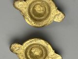 two small gold objects are sitting on a gray surface