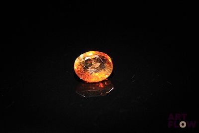 a close up of an orange diamond on a black surface