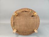 a close up of a round wicker bag on a white surface