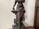a statue of a woman holding a basket of flowers on a table
