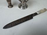 two silver vases and a knife sitting on a table