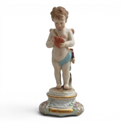 figurine of a cupid holding a yarn ball and knitting needles