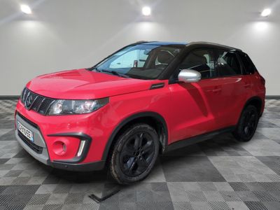 a red suzuki vitax parked in a room with a checkered floor