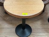 a wooden table with a black metal base on a wooden floor