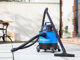 a bagged vacuum on a patio with a table and chairs in the background