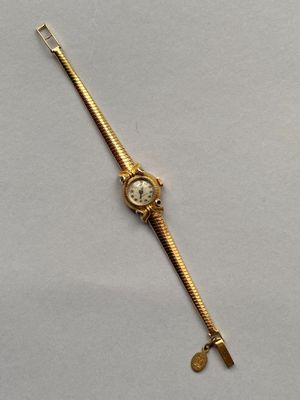 un gros plan d'une montre-bracelet en or sur laquelle est posée une clé