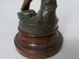 a bronze statue of a bird perched on a wooden base