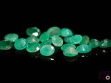 a pile of green emeralds on a black surface