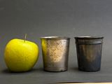 three cups sitting next to a green apple on a table
