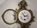 a gold clock with roman numerals and a magnifying glass