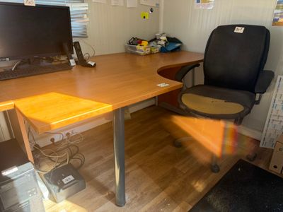 a desk with a computer and a chair in the room