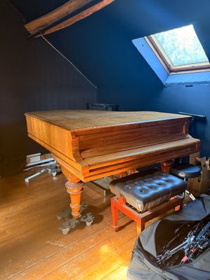 un piano dans un coin de la pièce, avec un vélo posé par terre