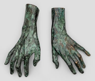 une paire de mains en bronze sur fond blanc