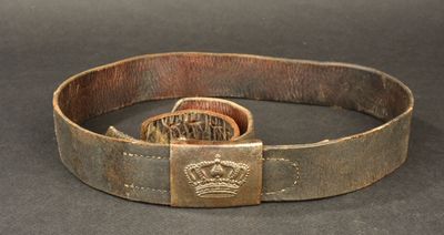 an old belt with a crown buckle on it on a table