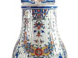 un vase bleu et blanc posé sur un socle, sur une surface blanche
