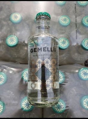 une bouteille de gin posée sur un lit orné d'un motif bleu et blanc