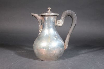 a silver coffee pot with a handle on a table