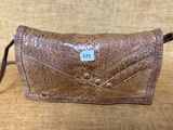 un sac à main en cuir marron muni d'une étiquette, posé sur un canapé