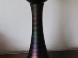 a black vase sitting on a wooden table next to a white wall