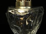 an image of a glass bottle with a gold lid on a black surface