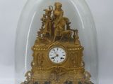 a gold clock under a glass dome on a table