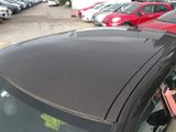 a black car parked in a parking lot with other cars in the background