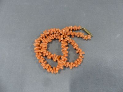 un collier composé de perles orange et orné d'un symbole de paix