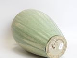 a green vase that is sitting on a white surface