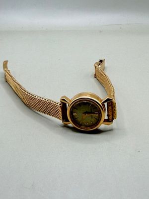 une montre-bracelet en or avec un cadran vert sur fond blanc