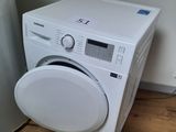 a white washing machine sitting on the floor next to a water heater