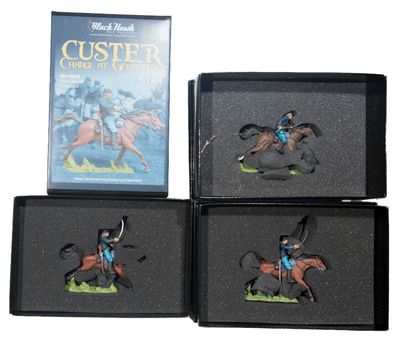 three miniature figurines of a man riding a horse in a box