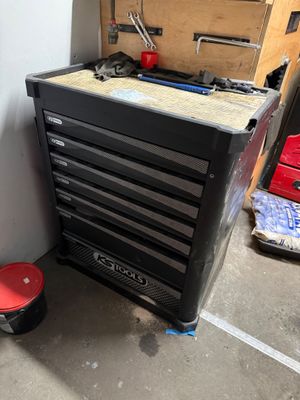 une armoire à outils noire et un tabouret rouge dans un garage