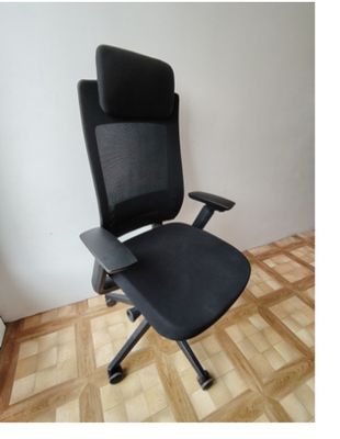 une photo d'une chaise de bureau noire posée sur un parquet en bois massif