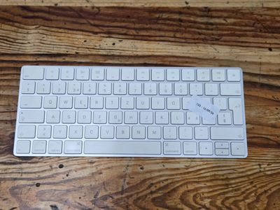 a white keyboard sitting on a wooden table next to a mouse