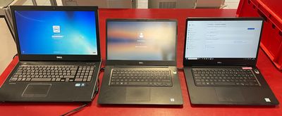 trois ordinateurs portables sont posés sur une table rouge dans une pièce