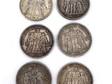 six silver coins of different sizes and shapes on a white surface