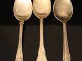three silver spoons are lined up in a row on a black surface